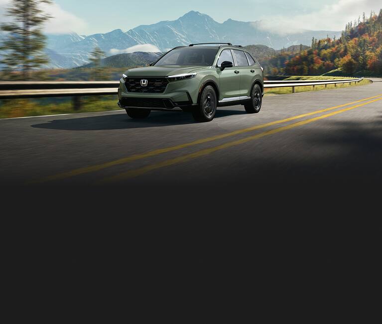 2027 Honda CR-V TrailSport Hybrid in Ash Green Metallic front driving on a winding mountain road (Compact Crossover SUV).